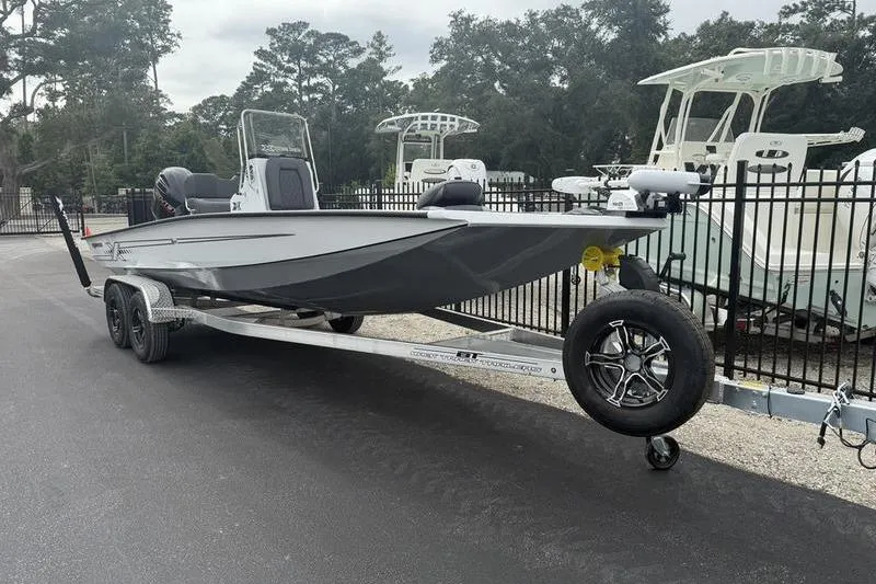 Slide: The Image of 2026 Xpress H22B Bay boat on trailer, parked outdoors near other boats. - 2
