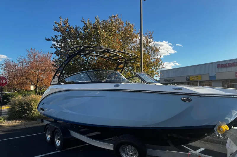 Slide: The Image of 2026 Yamaha Boats 252SD on trailer, parked outdoors with autumn trees in background. - 13