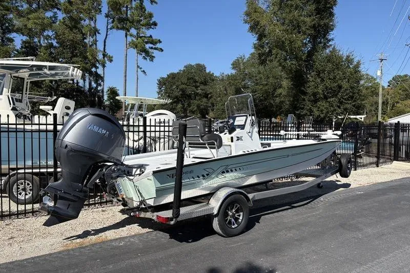 Slide: The Image of 2026 Xpress H20B Bay boat on trailer with Yamaha outboard, parked near other boats. - 2