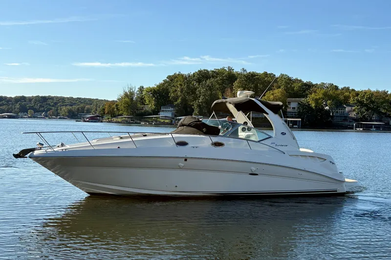 The Image of 2004 Sea Ray 320 Sundancer boat on a serene lake with wooded shoreline. - 0