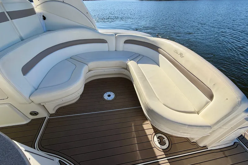 Slide: The Image of 2004 Sea Ray 320 Sundancer boat with white seating and wooden deck by the water. - 11