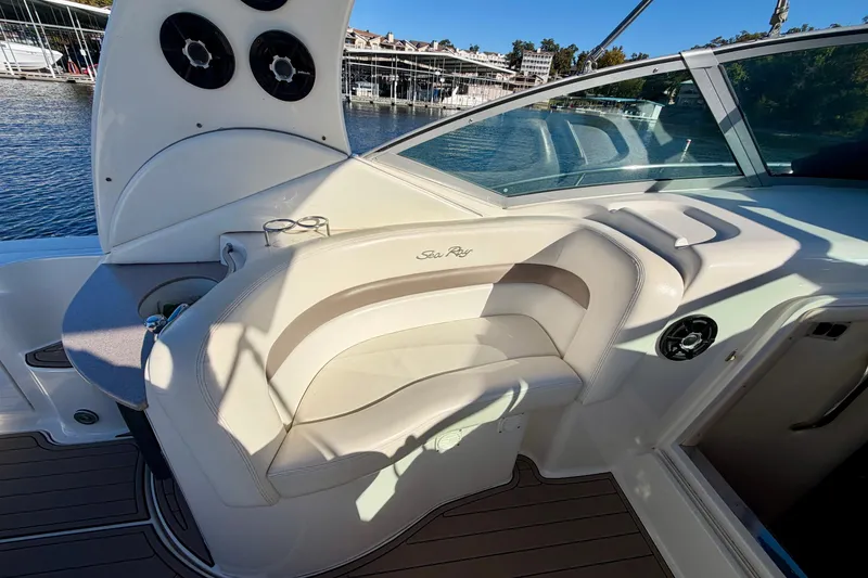 Slide: The Image of 2004 Sea Ray 320 Sundancer cockpit with seating, speakers, and waterfront view. - 14