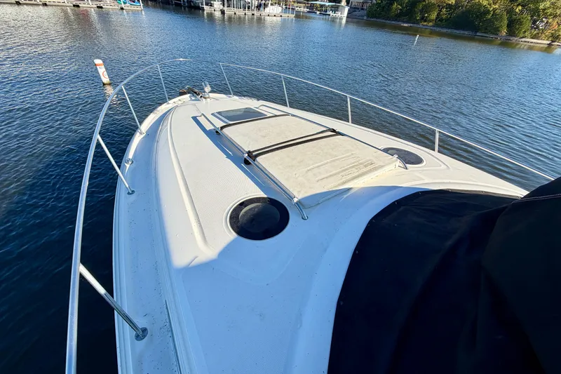 Slide: The Image of 2004 Sea Ray 320 Sundancer yacht on calm water, showcasing spacious deck and sleek design. - 22