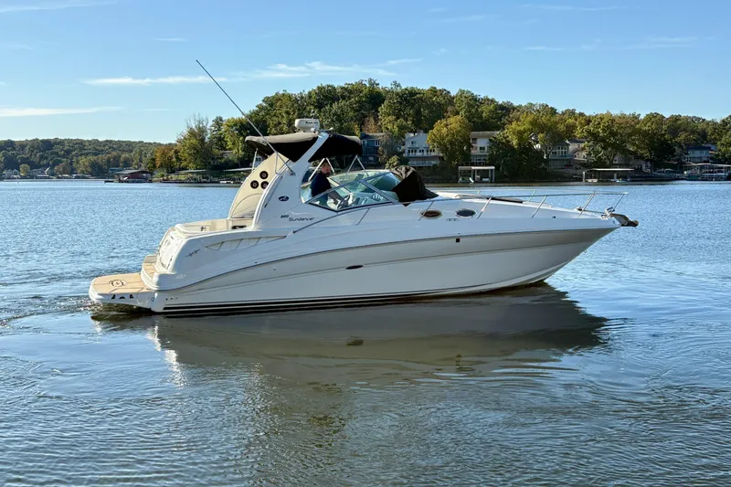 Slide: The Image of 2004 Sea Ray 320 Sundancer cruising on a serene lake with lush green shoreline. - 4