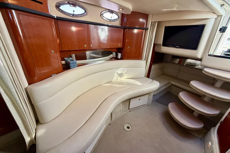 Slide: The Image of Interior of 2004 Sea Ray 320 Sundancer with curved seating and wooden cabinetry. - 42