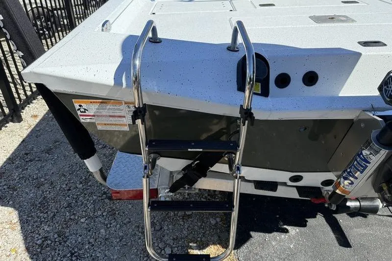 Slide: The Image of 2026 Xpress H20B Bay boat with ladder and motor, parked on gravel. - 17