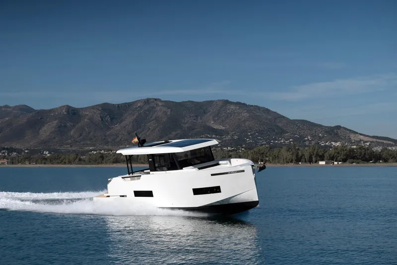 Slide: The Image of 2026 De Antonio Yachts 50 Coupe cruising on a serene lake with mountain backdrop. - 2