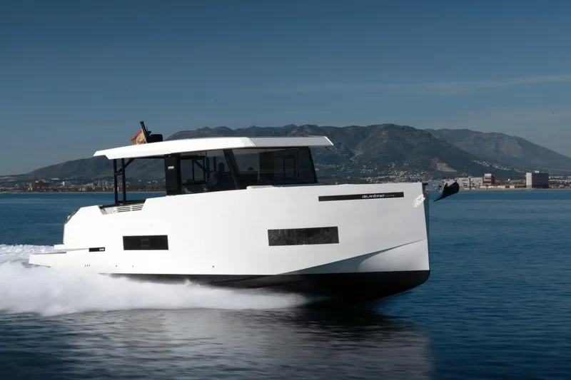 Slide: The Image of 2026 De Antonio Yachts 50 Coupe cruising on calm waters with mountainous backdrop. - 5