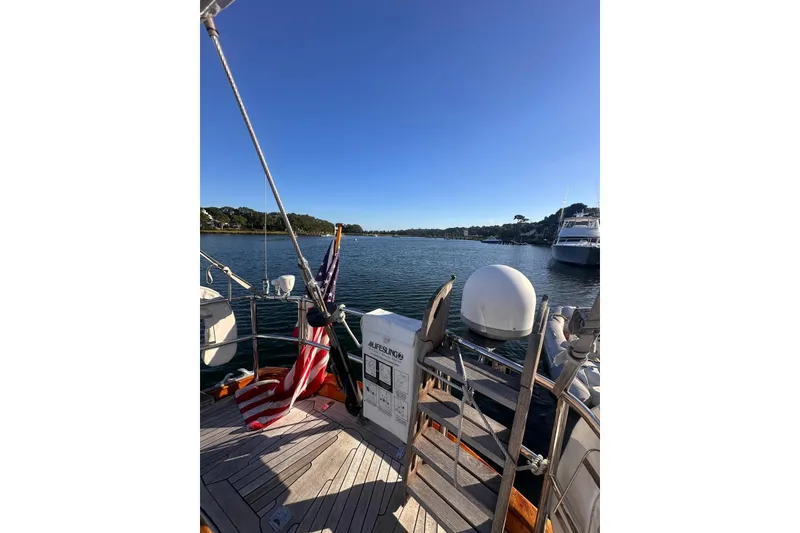 Slide: The Image of 1983 Camper & Nicholsons Cutter Rig sailboat deck with American flag, overlooking serene harbor. - 13