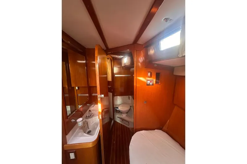 Slide: The Image of Interior of 1983 Camper & Nicholsons Cutter Rig, featuring wood paneling and compact bathroom. - 24