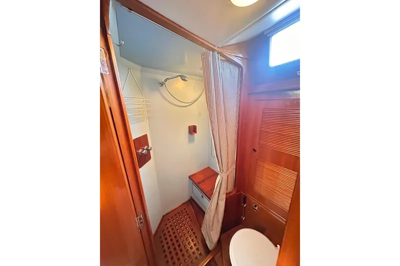 Slide: The Image of 1983 Camper & Nicholsons Cutter Rig bathroom with shower, wooden accents, and striped curtain. - 40