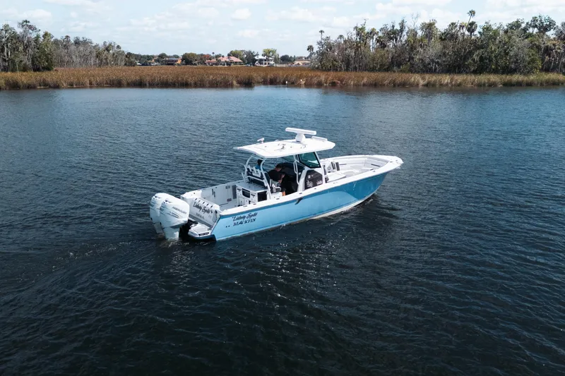 Slide: The Image of 2021 Blackfin 332 CC boat cruising on a calm lake with scenic shoreline. - 107