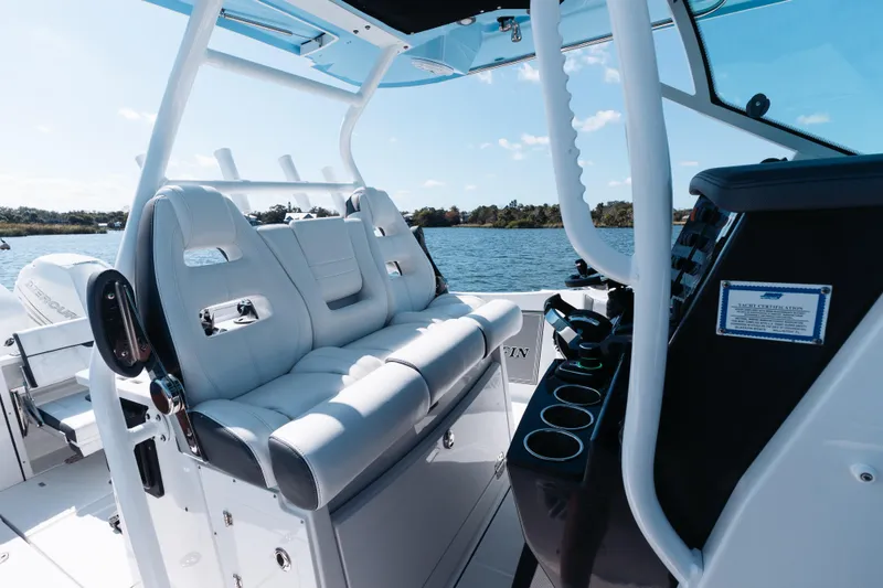 Slide: The Image of 2021 Blackfin 332 CC boat interior with luxurious seating and control panel on a sunny day. - 17