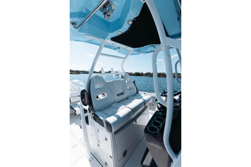 Slide: The Image of 2021 Blackfin 332 CC boat interior with white seating and blue canopy on water. - 18
