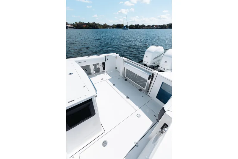 Slide: The Image of 2021 Blackfin 332 CC boat deck with twin engines on a calm lake. - 69