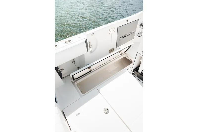 Slide: The Image of 2021 Blackfin 332 CC boat interior with open storage compartment by the water. - 92