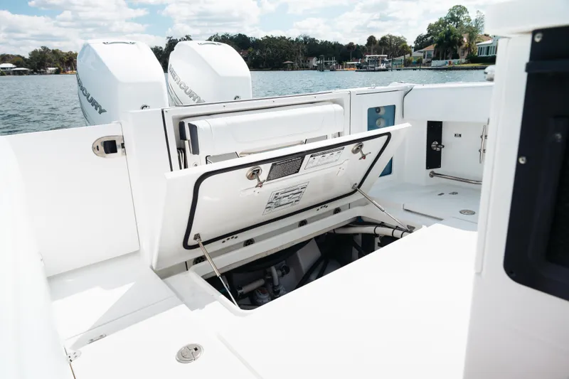 Slide: The Image of 2021 Blackfin 332 CC boat with open storage compartment, twin Mercury engines, and scenic water backdrop. - 95