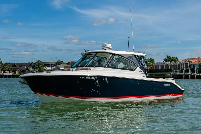 The Image of 2017 Pursuit DC 295 Dual Console boat on calm water, with houses in the background. - 0