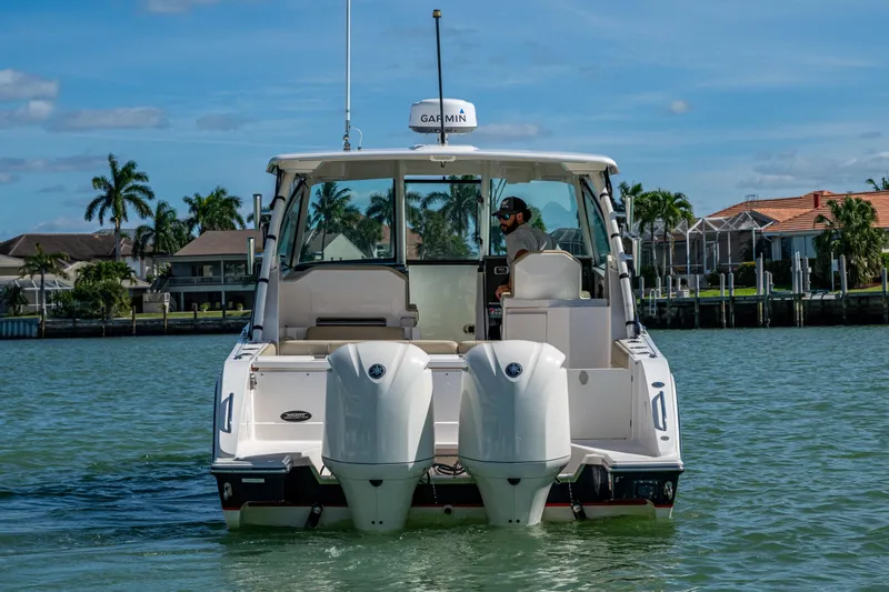 Slide: The Image of 2017 Pursuit DC 295 Dual Console boat on water, with palm trees and houses in background. - 13