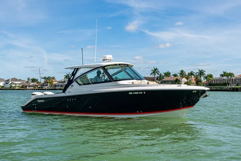 Slide: The Image of 2017 Pursuit DC 295 Dual Console boat on calm water, with palm trees in the background. - 4