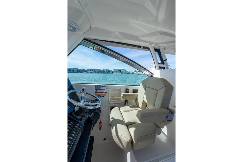 Slide: The Image of 2017 Pursuit DC 295 Dual Console interior with steering wheel and beige captain's chair. - 43