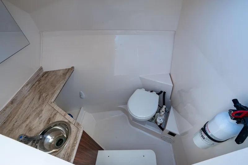 Slide: The Image of 2017 Pursuit DC 295 Dual Console boat bathroom with sink, toilet, and fire extinguisher. - 46