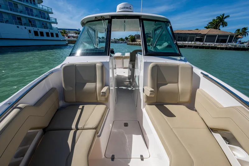 Slide: The Image of 2017 Pursuit DC 295 Dual Console boat interior with beige seating, docked in sunny marina. - 48