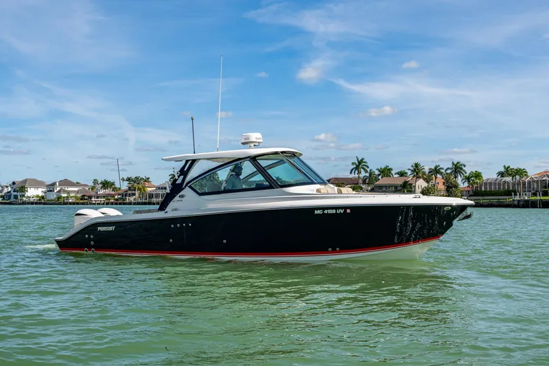 Slide: The Image of 2017 Pursuit DC 295 Dual Console boat on calm water, with palm trees in the background. - 5
