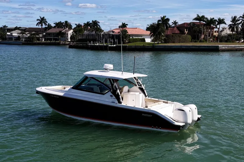 Slide: The Image of 2017 Pursuit DC 295 Dual Console boat on calm water near waterfront homes. - 50