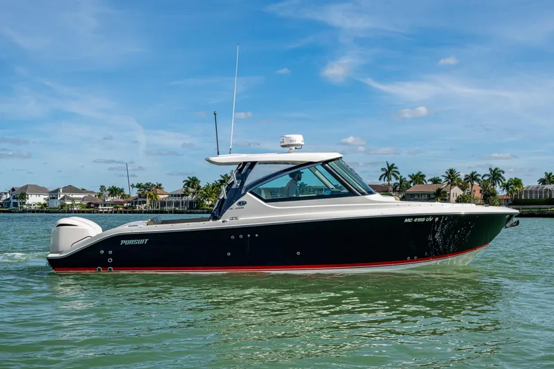 Slide: The Image of 2017 Pursuit DC 295 Dual Console boat on calm water, with a scenic coastal backdrop. - 8