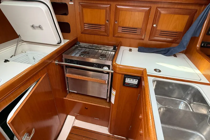 Slide: The Image of Galley kitchen in 2000 Beneteau 361 sailboat with stove, sink, and wooden cabinetry. - 15