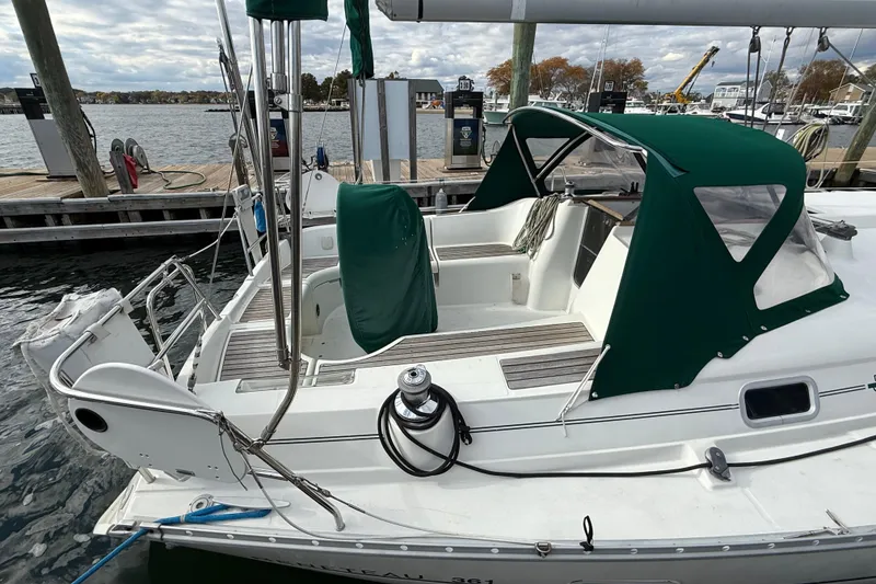 Slide: The Image of 2000 Beneteau 361 sailboat docked, featuring green canopy and spacious cockpit. - 7