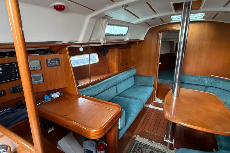 Slide: The Image of Interior of 2000 Beneteau 361 sailboat with wood finish and teal seating. - 8