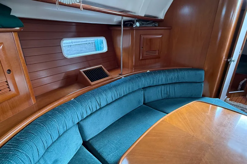 Slide: The Image of Interior of 2000 Beneteau 361 sailboat with curved seating and wooden finishes. - 9