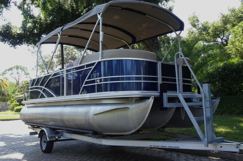 Slide: The Image of 2023 Sylvan Mirage Fish 820 Party Fish pontoon boat on trailer, parked outdoors. - 3