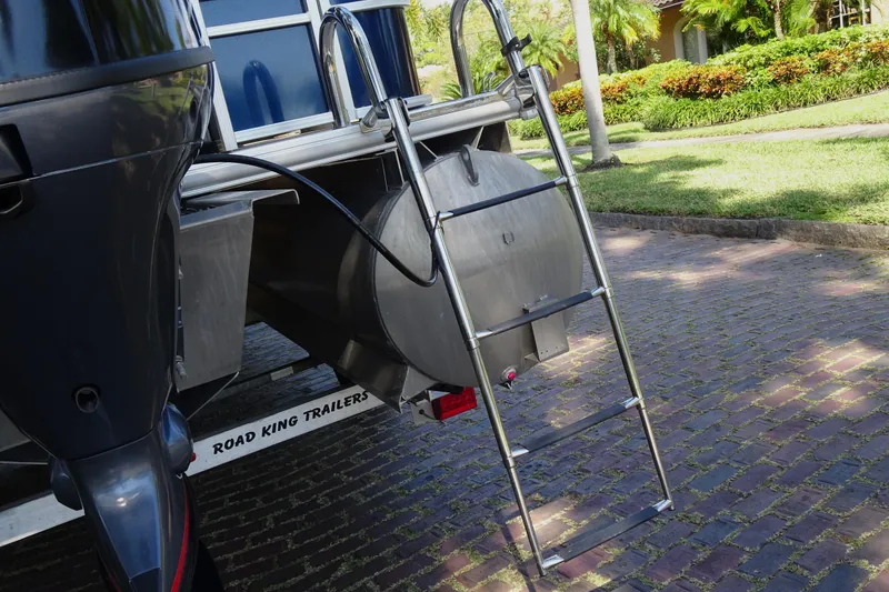 Slide: The Image of 2023 Sylvan Mirage Fish 820 Party Fish boat with ladder and trailer on cobblestone path. - 9