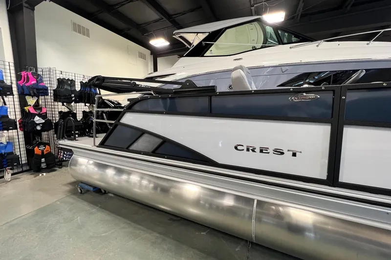 Slide: The Image of 2026 Crest Conquest 230 SLSC pontoon boat displayed indoors with life jackets nearby. - 4