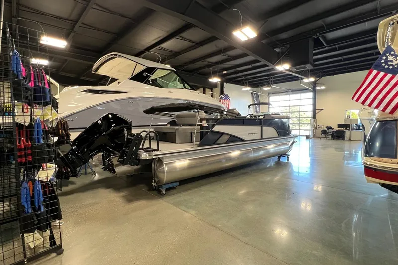 Slide: The Image of 2026 Crest Conquest 230 SLSC pontoon boat displayed in a showroom with American flags. - 7