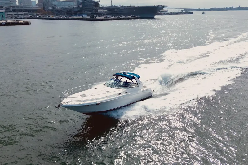 The Image of 1999 Sea Ray Sundancer 400 cruising on open water near urban skyline. - 1