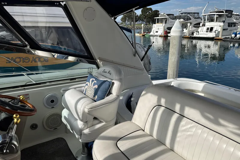 Slide: The Image of 1999 Sea Ray Sundancer 400 interior with white seating, steering wheel, and marina view. - 10