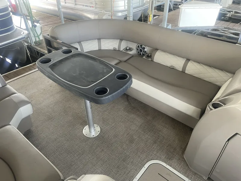 Slide: The Image of 2020 Bennington SSRFBXP boat interior with cushioned seating and table, docked at marina. - 24