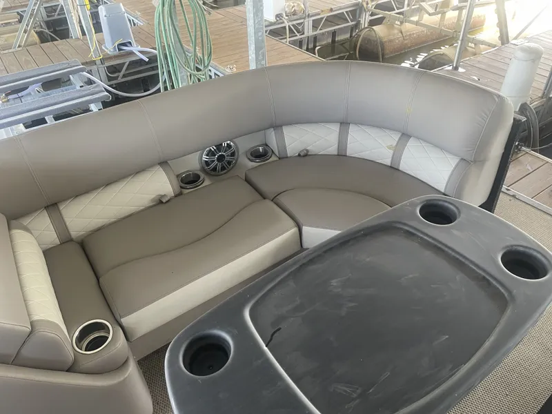 Slide: The Image of 2020 Bennington SSRFBXP boat interior with beige seating and table, featuring cup holders and speaker. - 25