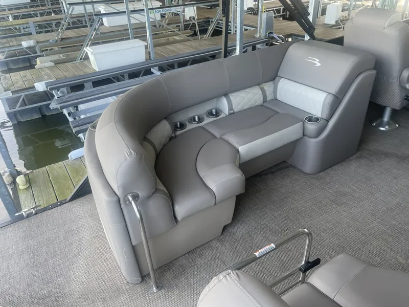 Slide: The Image of 2020 Bennington SSRFBXP boat interior with gray seating and cup holders at a dock. - 29