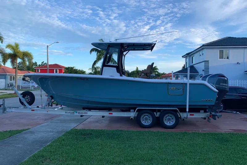 Slide: The Image of 2022 Sea Hunt Gamefish 25 boat on trailer, parked near palm trees at sunset. - 2