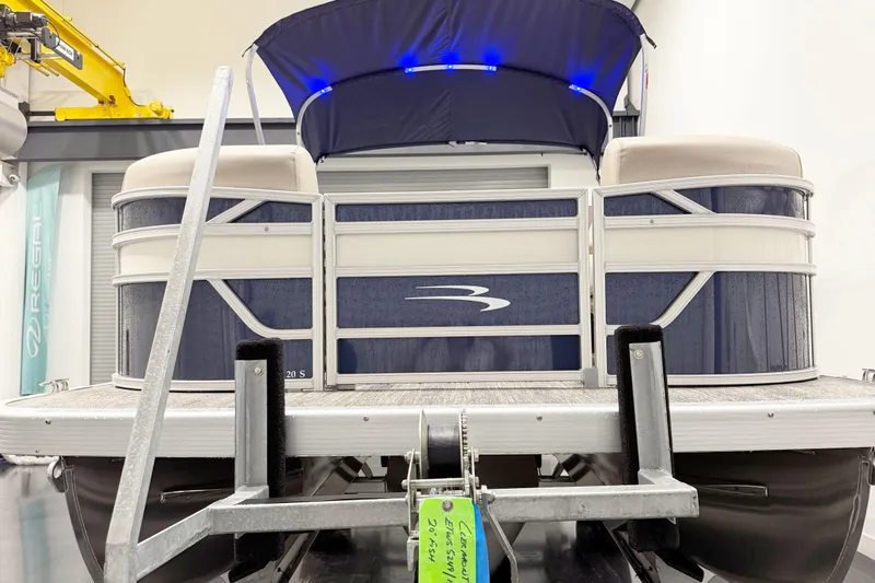 Slide: The Image of 2025 Bennington 20S pontoon boat with blue canopy and sleek design in showroom. - 5