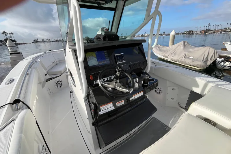 Slide: The Image of 2019 Blackfin 272 CC boat interior with helm, docked by calm waters. - 18