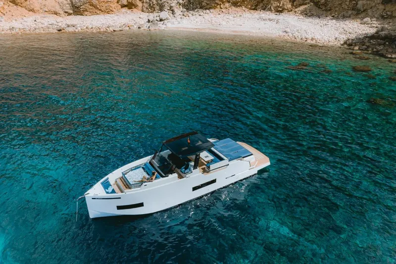 Slide: The Image of ```markdown
Luxurious 2026 De Antonio Yachts 50 Open cruising in clear turquoise waters near a rocky shoreline.
``` - 6