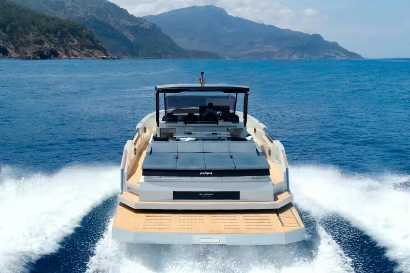 Slide: The Image of 2026 De Antonio Yachts 50 Open cruising on blue ocean with scenic mountain backdrop. - 12