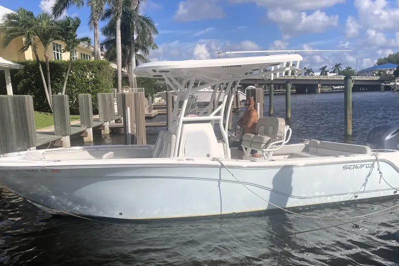 Slide: The Image of 2021 Sea Fox 249 Avenger boat docked by palm trees and waterfront homes. - 2