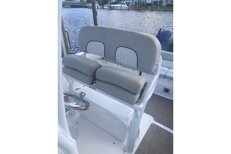 Slide: The Image of 2021 Sea Fox 249 Avenger boat seating with steering wheel, docked by the water. - 44
